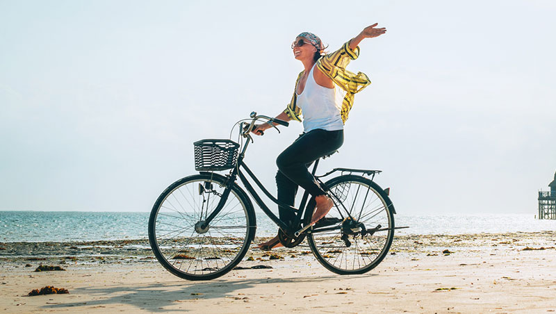 chica montando en bici en la playa