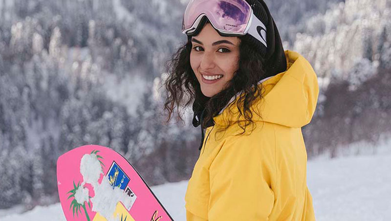 chica con ski en la nieve y abrigo amarillo