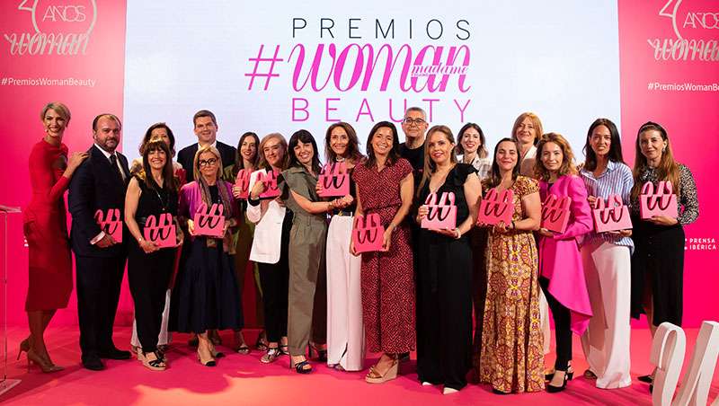 mujeres recibiendo premio escenario posando fondo rosa