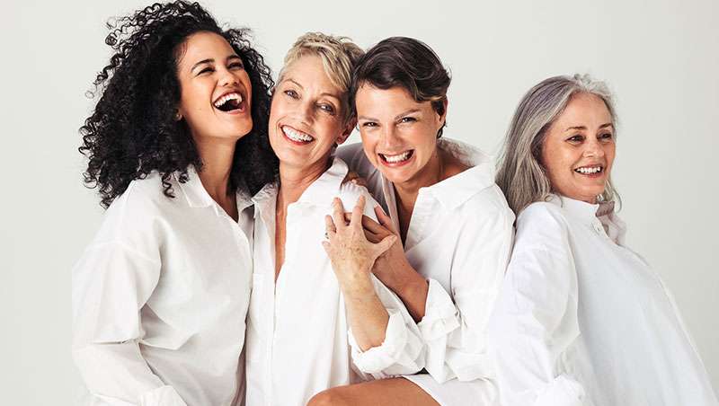 mujeres diferentes edades sonriendo camisa blanca
