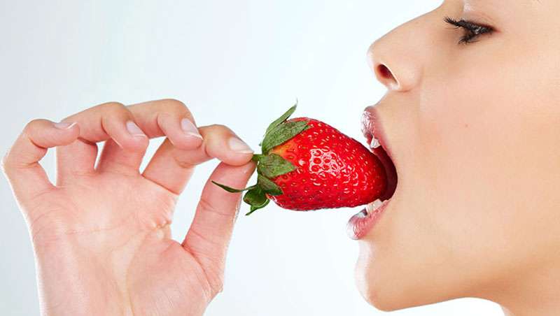 chica comiendose una fresa con boca abierta