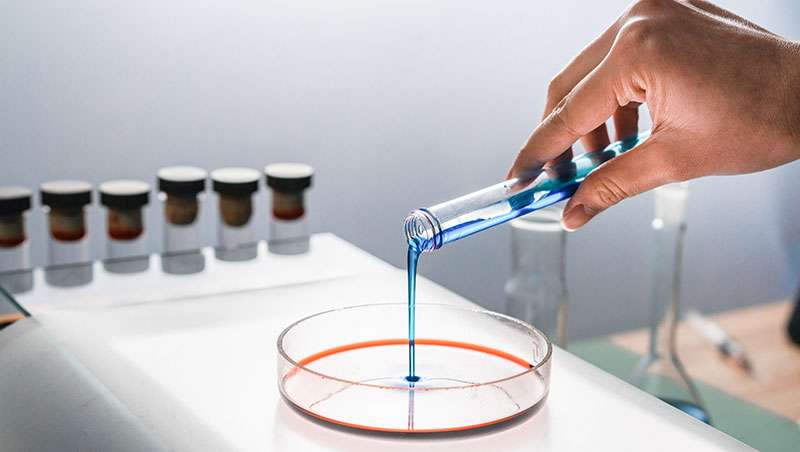 laboratorio vertiendo liquido azul manos