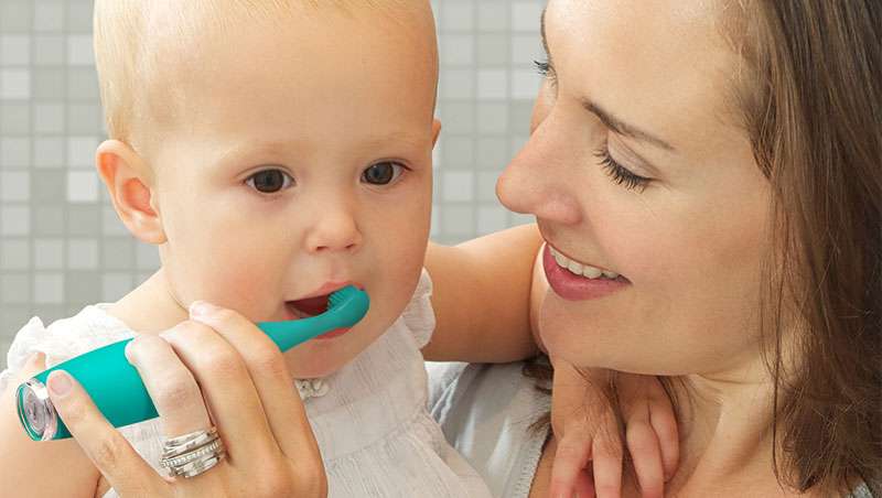 madre cepillando dientes a su bebe