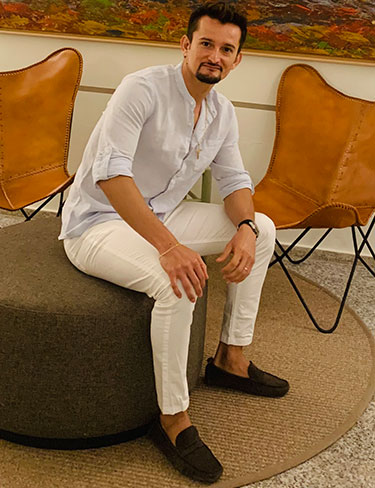 hombre sentado con pantalones blancos y camisa auzl